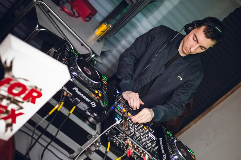 Overhead view of a DJ mixing on Pioneer decks beside the Vortex lightbox.