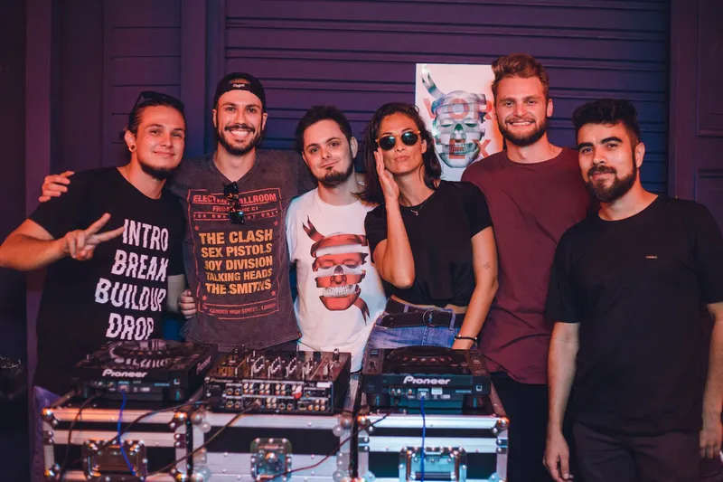 The Vortex crew posing behind the decks in front of the skull poster.