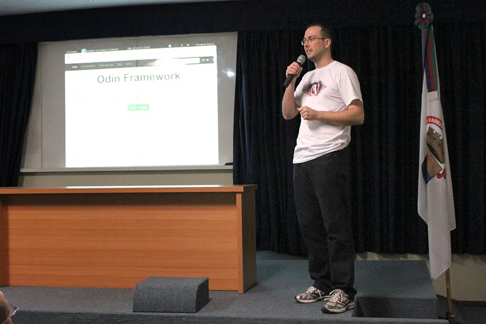 Me on stage at WordCamp Porto Alegre 2013, mic in hand, presenting in front of a projected slide.